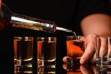 Photo of Bartender pouring alcohol drink into shot glass at mirror bar counter, closeup