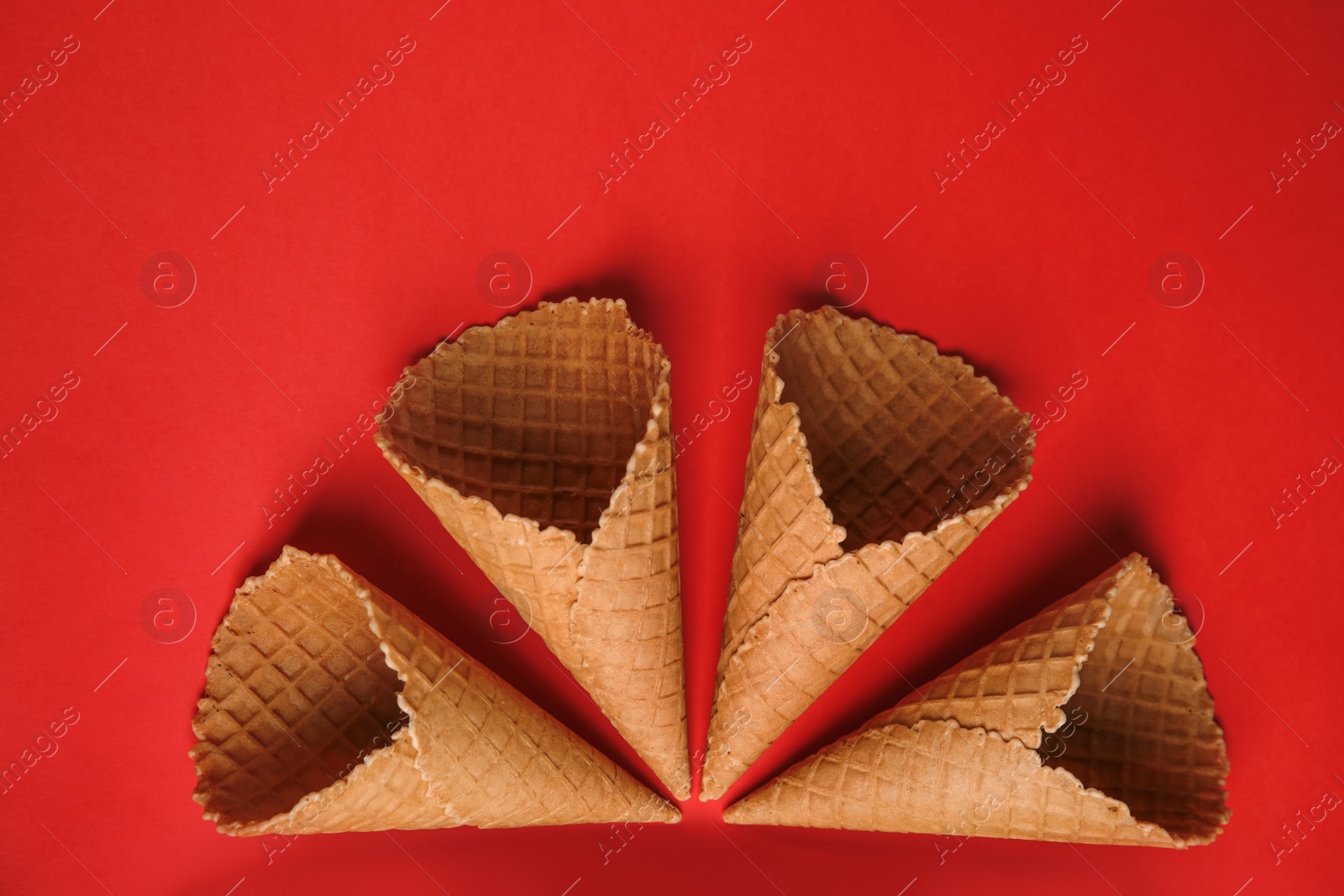 Photo of Waffle empty ice cream cones on color background, flat lay