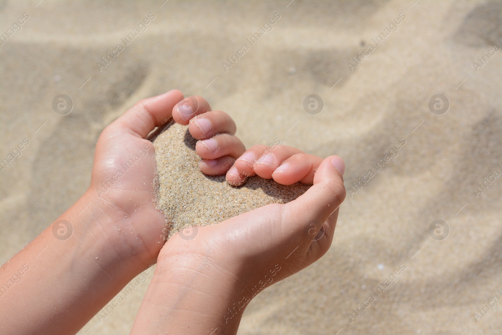 Photo of Child holding sand in hands outdoors, closeup. Fleeting time concept