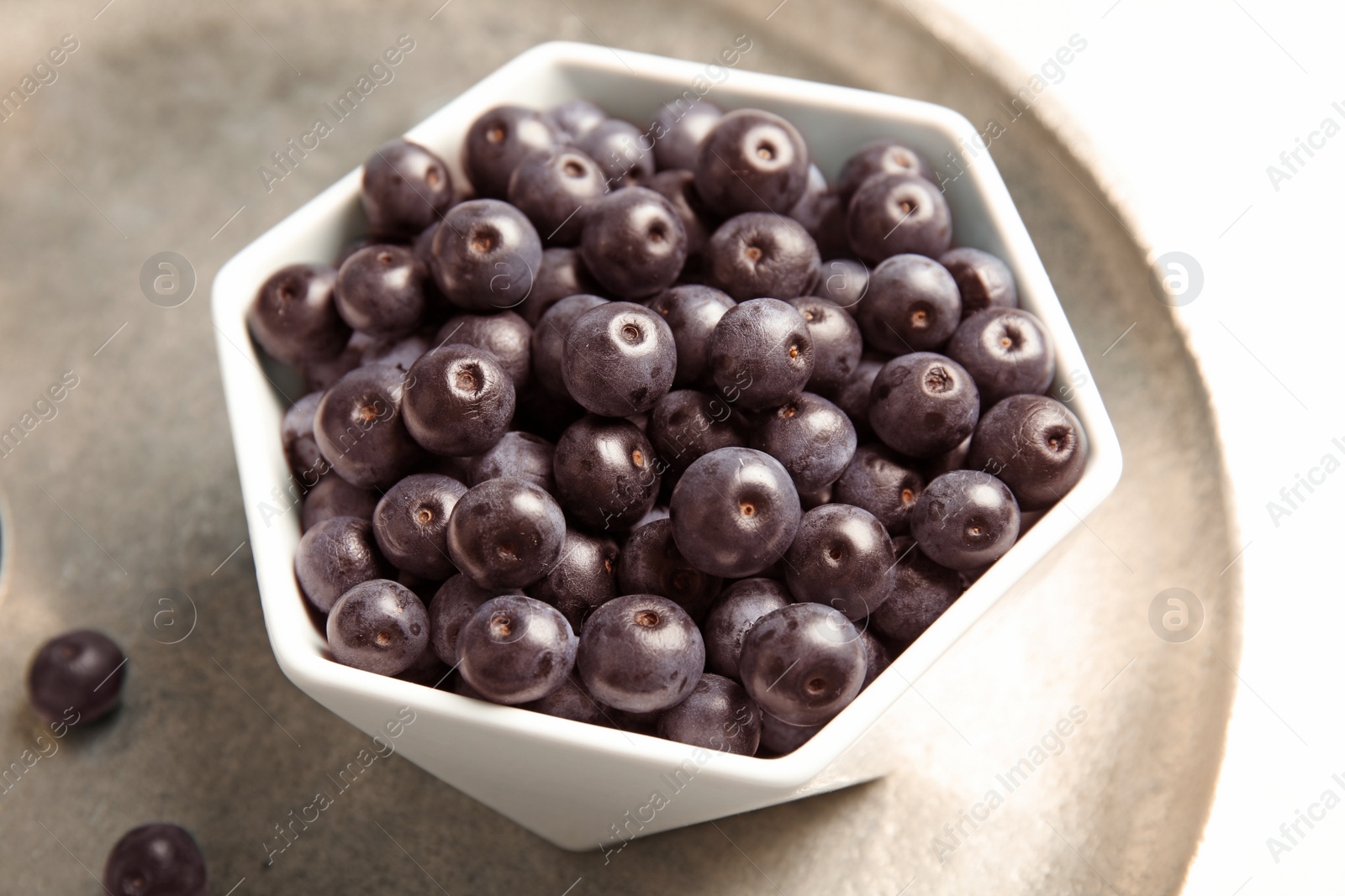 Photo of Bowl with fresh acai berries on tray, closeup