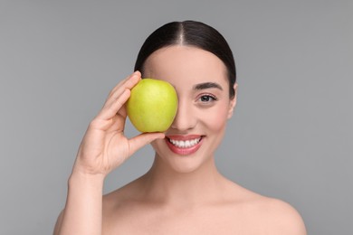 Photo of Beautiful young woman with apple on grey background