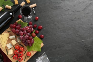 Tasty red wine and snacks on black table, flat lay. Space for text