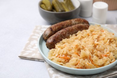 Photo of Plate with sauerkraut and sausages on light grey table, closeup. Space for text