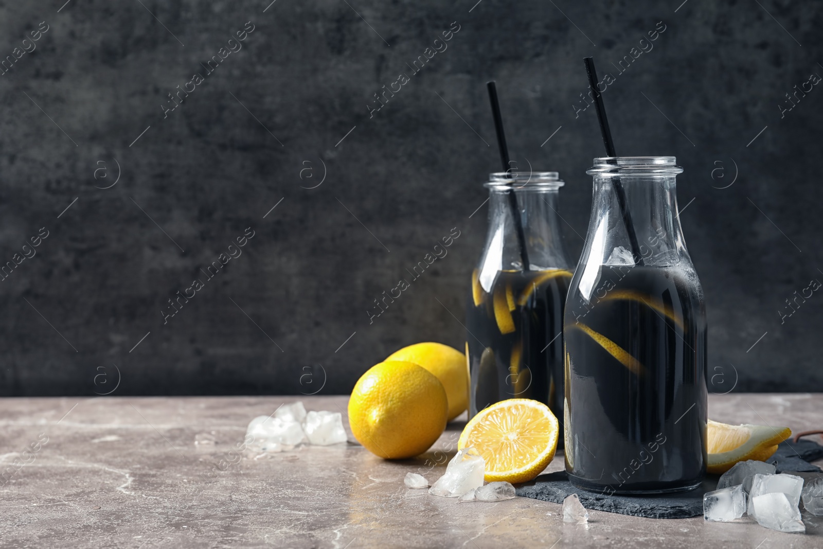 Photo of Bottles with natural black lemonade on table