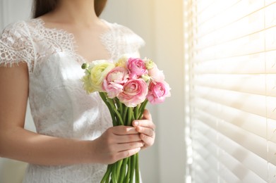 Photo of Bride with beautiful ranunculus bouquet indoors, closeup. Space for text