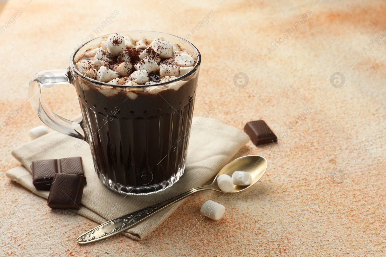 Photo of Cup of aromatic hot chocolate with marshmallows and cocoa powder served on beige table, closeup. Space for text