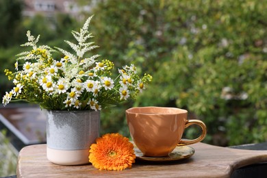 Cup of delicious chamomile tea and fresh flowers outdoors on sunny day. Space for text