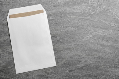Photo of White paper envelope on grey background, top view. Space for text