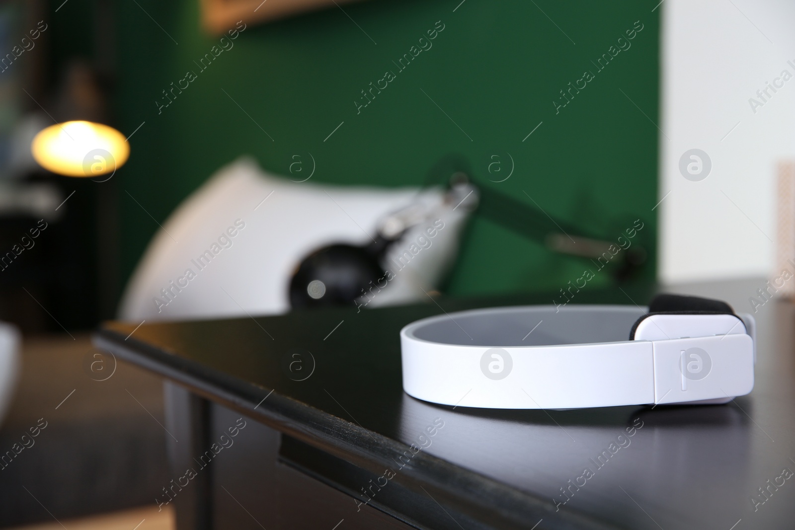 Photo of Stylish modern wireless headphones on table against blurred background, space for text