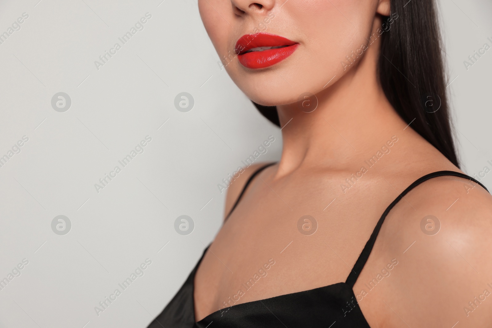 Photo of Young woman wearing beautiful red lipstick on light gray background, closeup