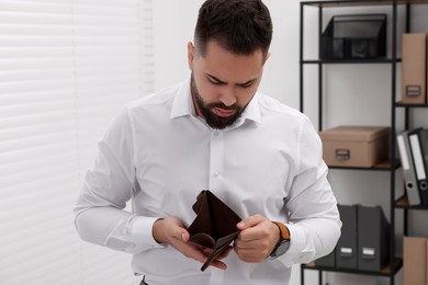 Upset man with empty wallet in office