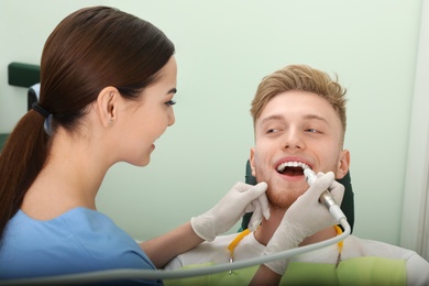 Photo of Professional dentist working with patient in modern clinic. Teeth care