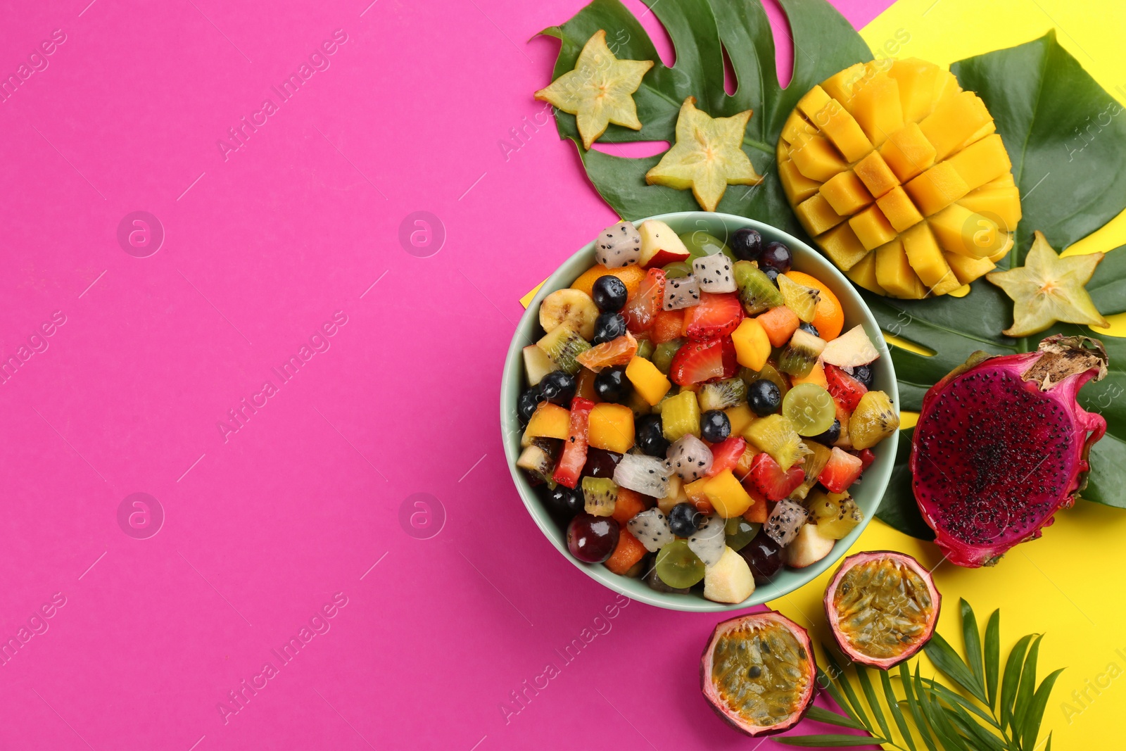 Photo of Flat lay composition with delicious exotic fruit salad on color background. Space for text