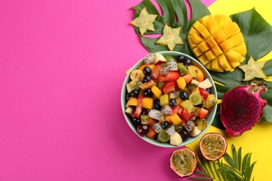 Flat lay composition with delicious exotic fruit salad on color background. Space for text
