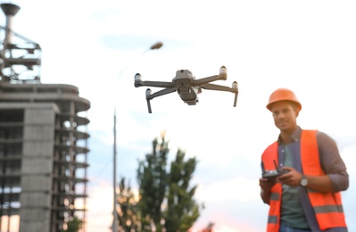 Photo of Builder operating drone with remote control at construction site, focus on quadcopter. Aerial survey