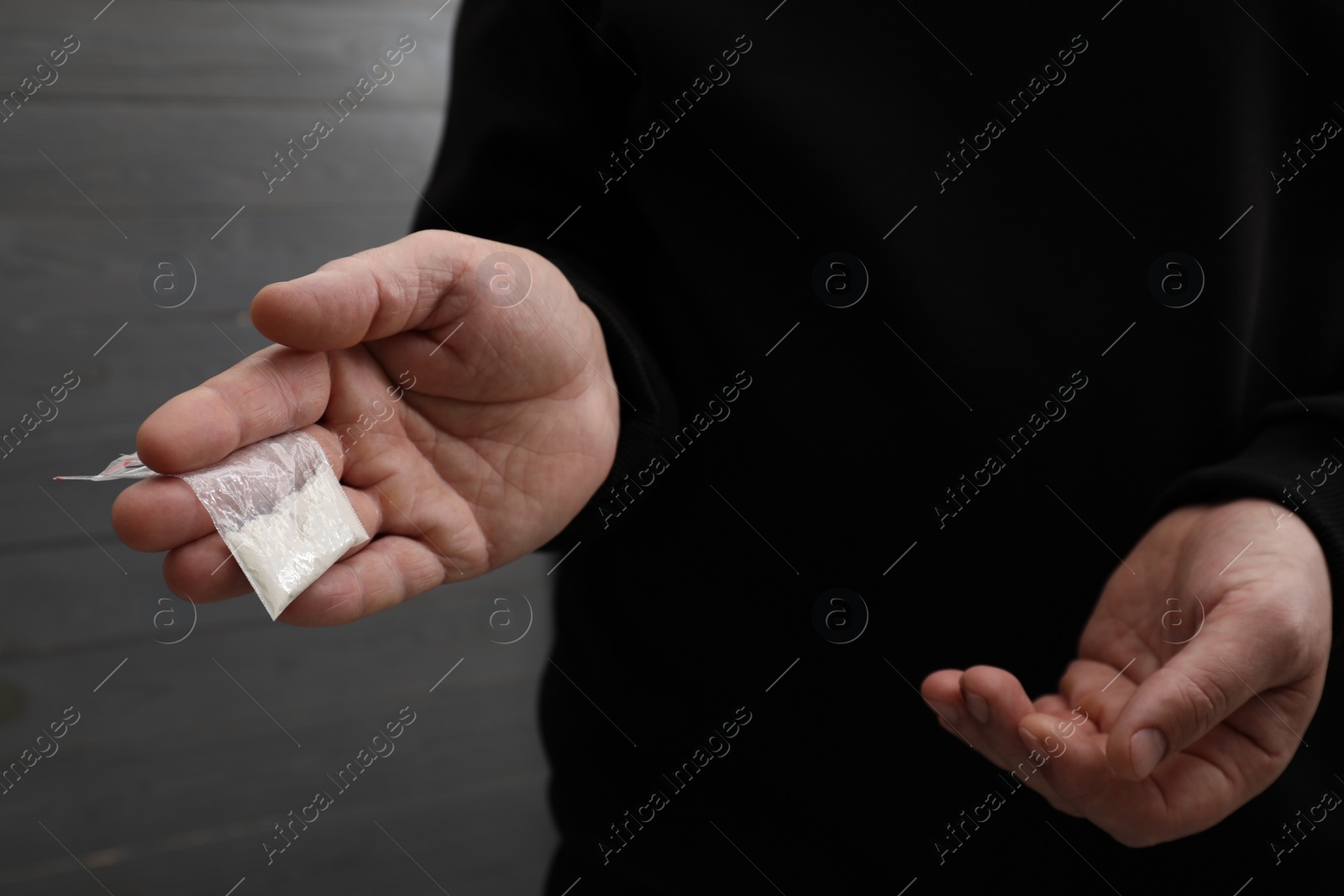 Photo of Drug addiction. Man with plastic bag of cocaine on grey background, closeup