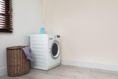 Photo of Modern washing machine and laundry basket indoors. Space for design