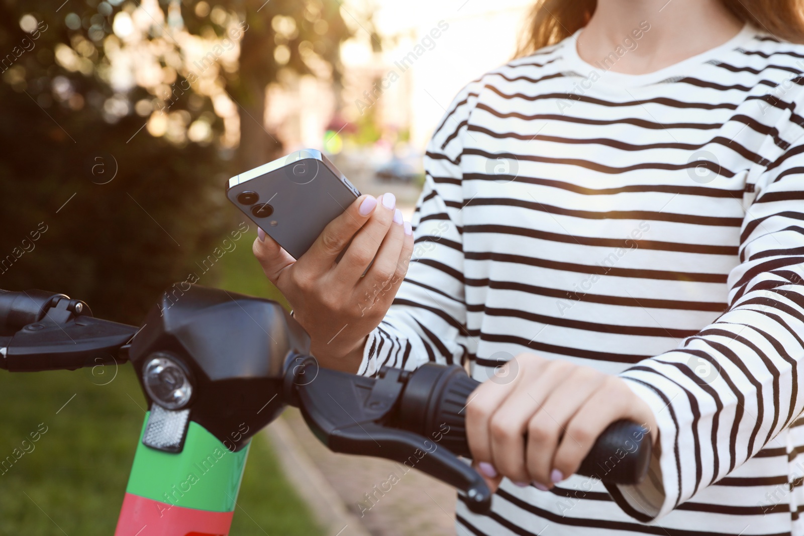 Photo of Woman using smartphone to pay and unblock electric kick scooter outdoors, closeup