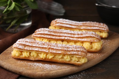 Photo of Delicious eclairs filled with cream on wooden table