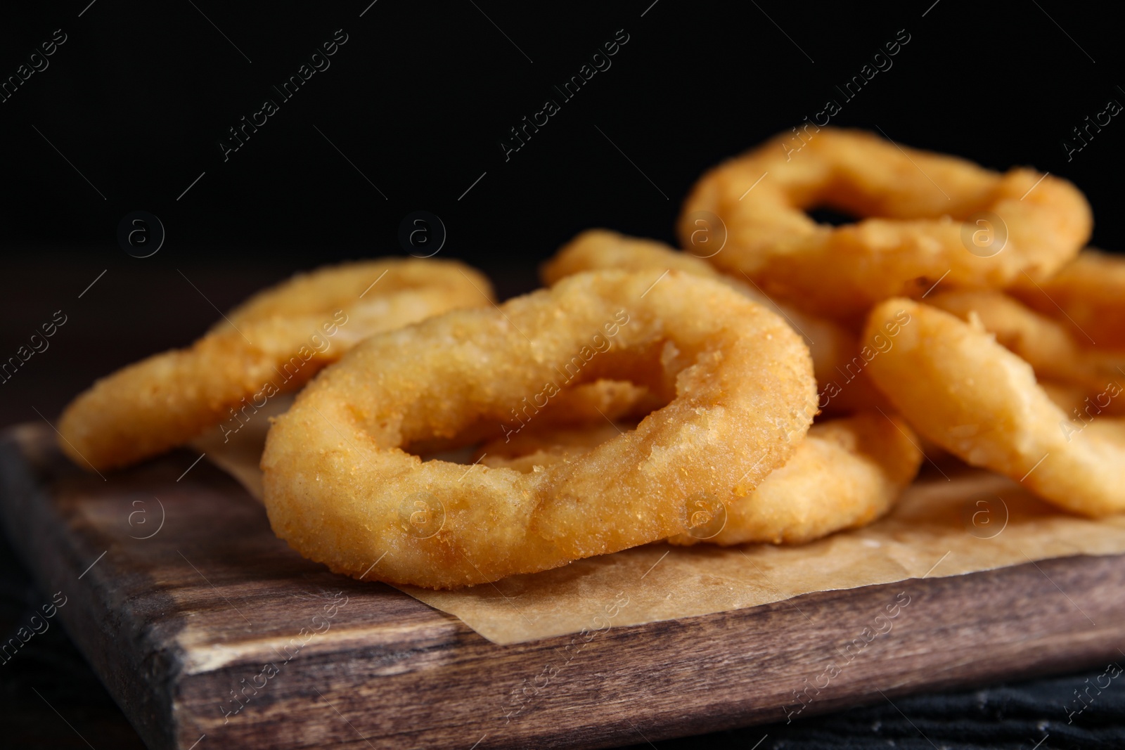 Photo of Fried onion rings served on wooden table, closeup