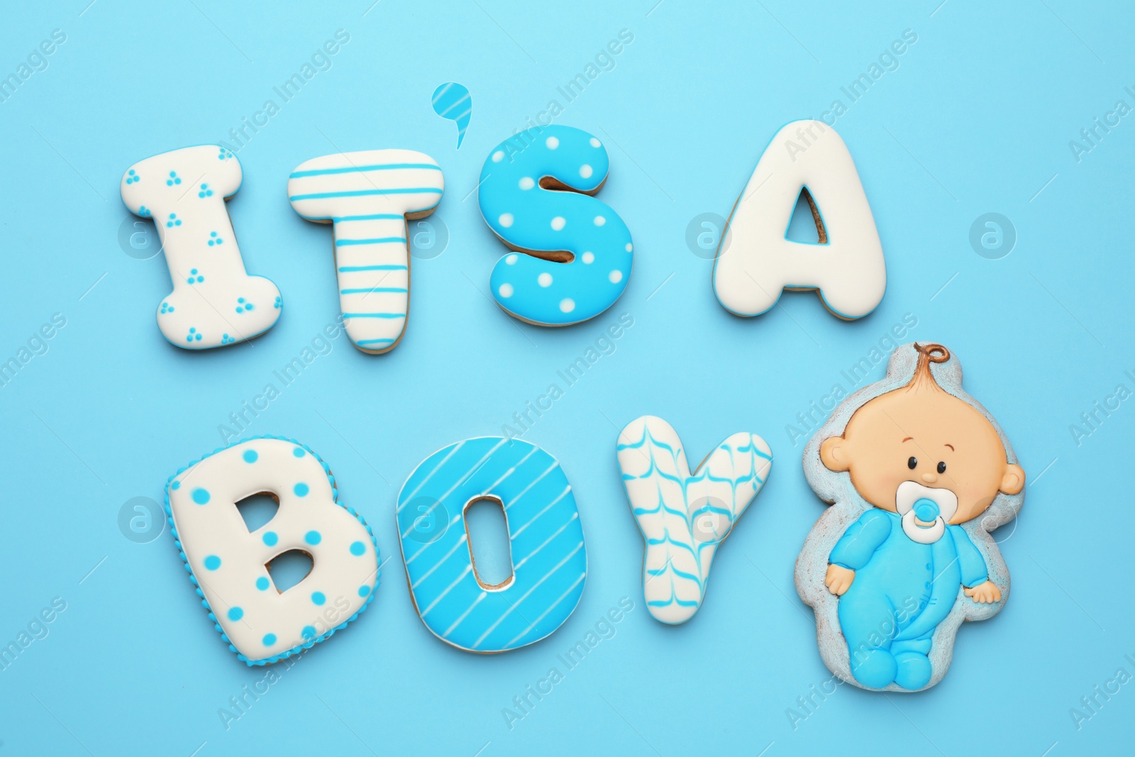 Photo of Phrase IT IS A BOY made of tasty cookies on light blue background, flat lay. Baby shower party