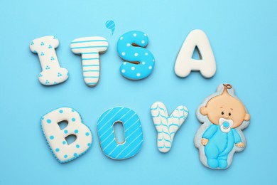 Photo of Phrase IT IS A BOY made of tasty cookies on light blue background, flat lay. Baby shower party