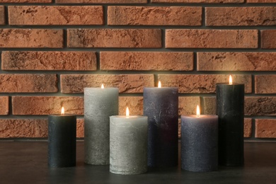 Photo of Burning candles on table against brick wall