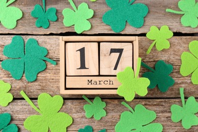 St. Patrick's day - 17th of March. Block calendar and felt clover leaves on wooden background, flat lay