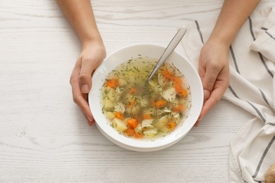 Sick woman eating fresh homemade soup to cure flu at table, top view