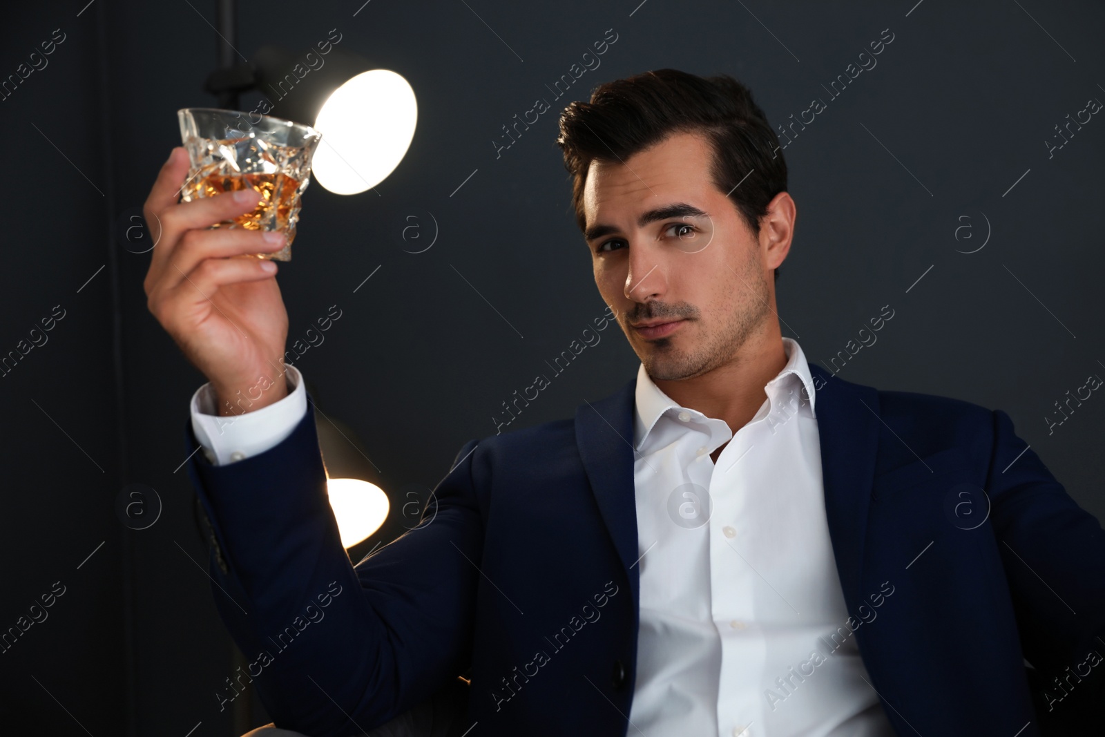 Photo of Young man with glass of whiskey indoors