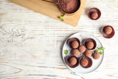 Photo of Plate with chocolate truffles on wooden background, top view. Space for text