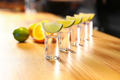 Vodka shots and lime slices on wooden bar counter