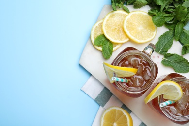 Photo of Delicious iced tea with lemon and mint on light blue background, flat lay. Space for text