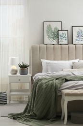 Bed with stylish grey linens near white wall in room