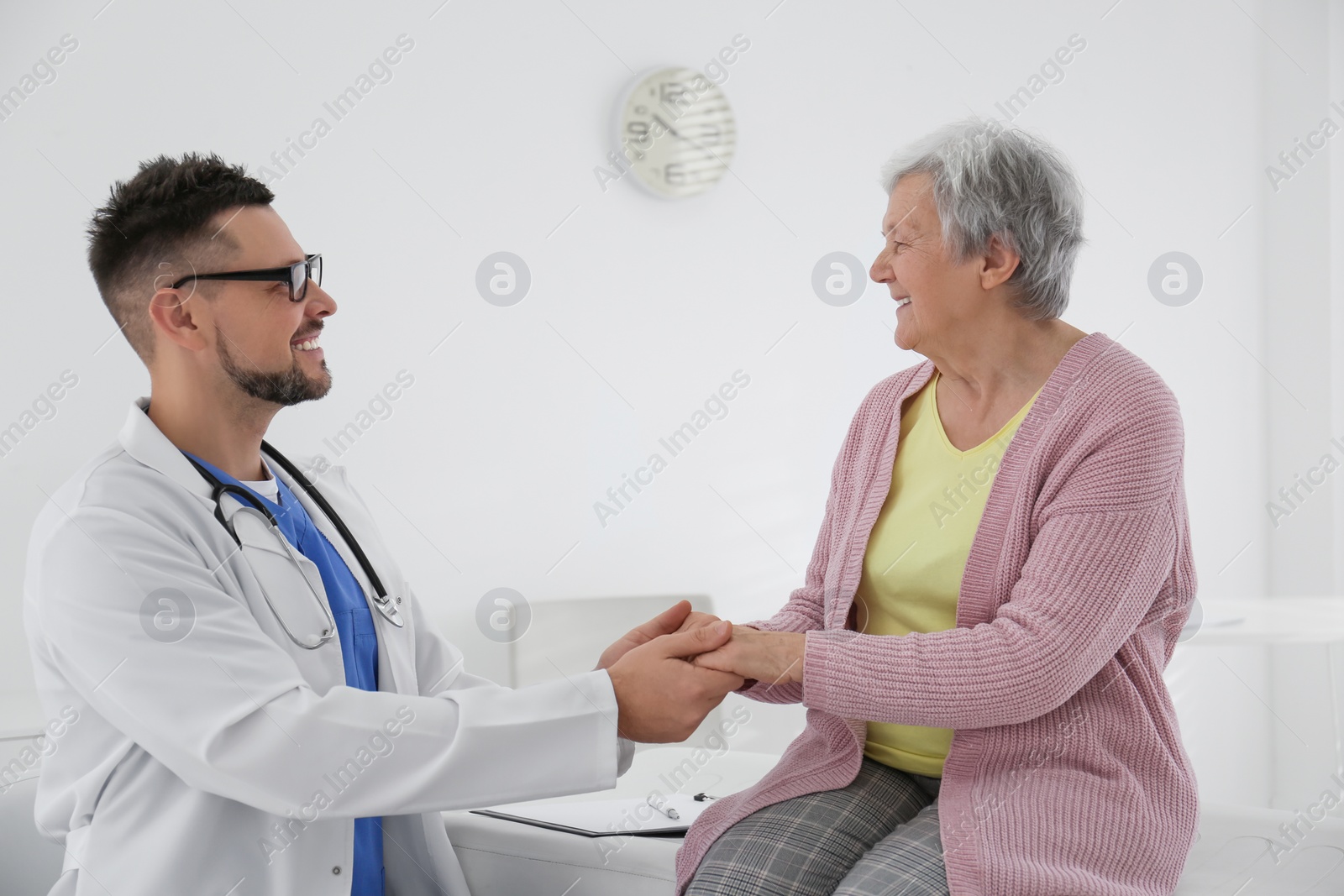 Photo of Doctor holding senior patient's hands in office