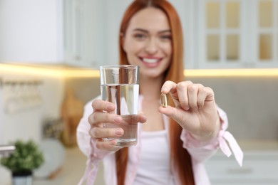 Photo of Beautiful young woman with vitamin pill and glass of water, selective focus