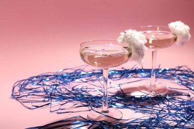 Photo of Tasty cocktail in glasses decorated with cotton candy and blue shiny streamers on pink background, space for text
