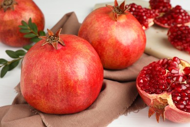 Fresh pomegranates and seeds on white table, closeup