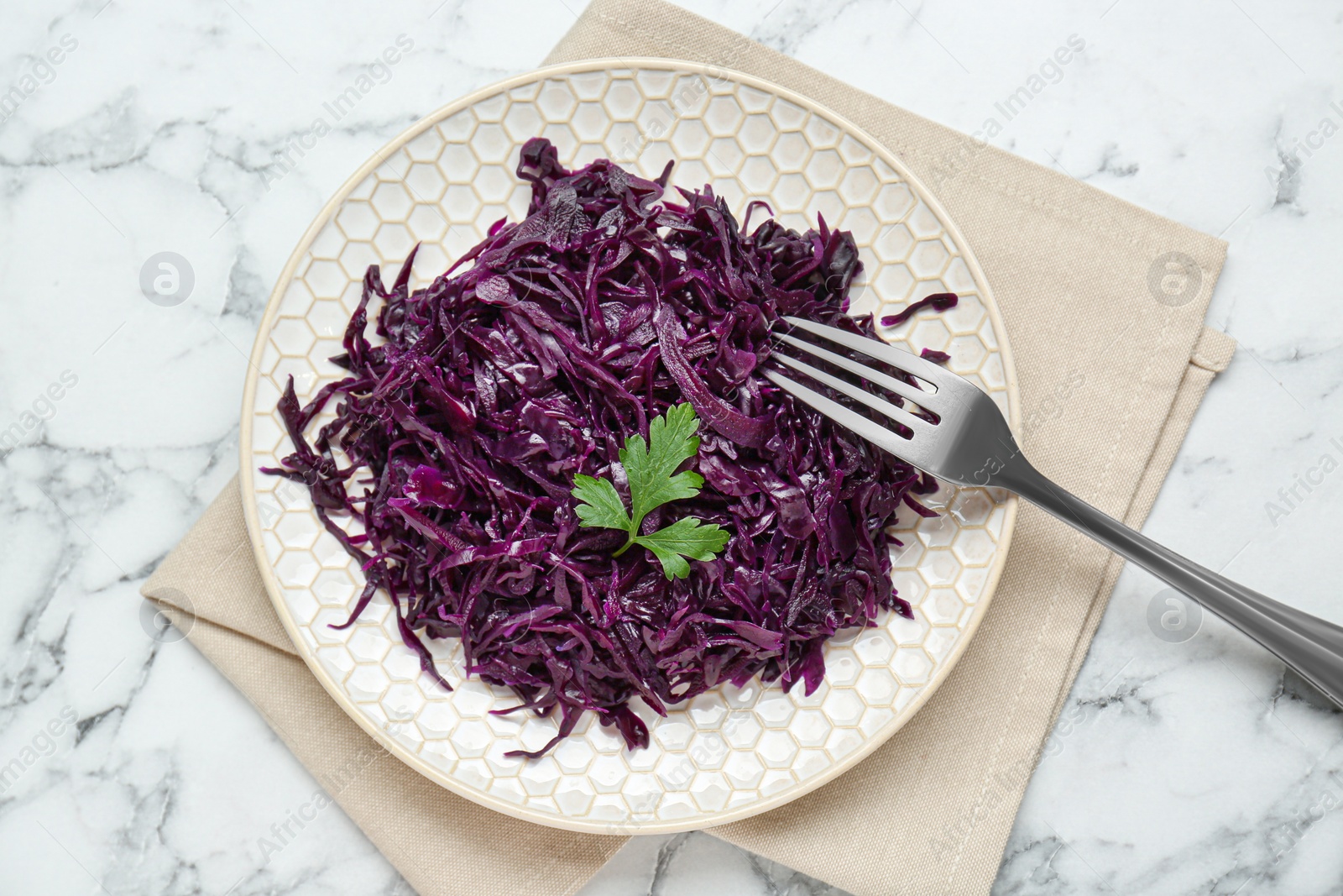 Photo of Tasty red cabbage sauerkraut with parsley served on white marble table, top view