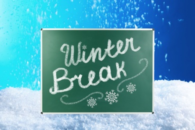 Text Winter Break and snowflakes on school chalkboard against snowdrift