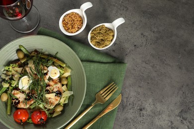 Photo of Delicious dish with tarragon, salad dressings and glass of wine served on grey table, flat lay. Space for text