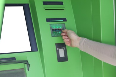 Photo of Woman inserting credit card into green cash machine, closeup