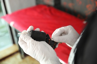 Photo of Professional artist checking tattoo machine in salon, closeup