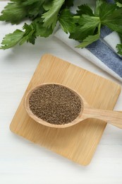 Photo of Spoon of celery seeds and fresh plant on white wooden table, flat lay