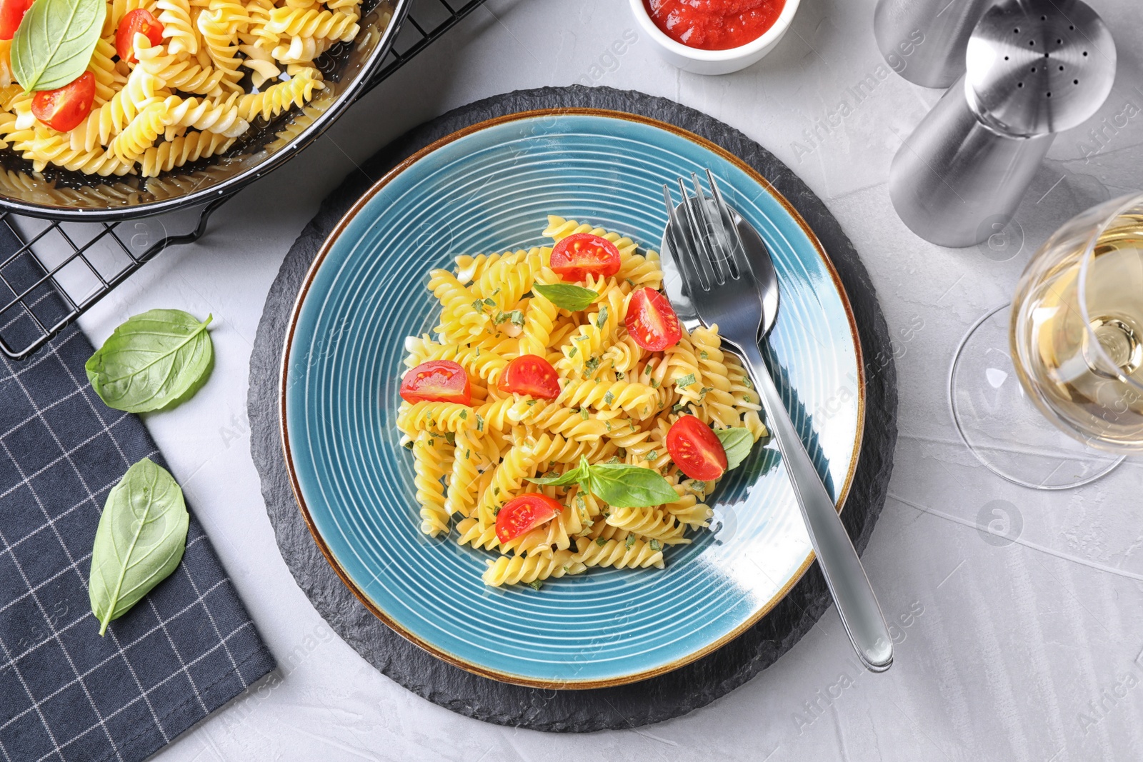 Photo of Delicious pasta with tomatoes and basil served on light table, flat lay