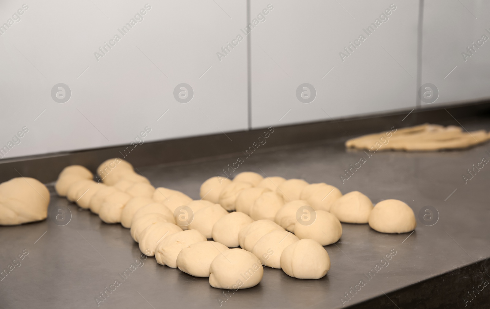 Photo of Raw dough on metal table in bakery workshop