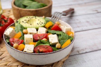 Bowl of tasty salad with tofu and vegetables on white wooden table, closeup. Space for text