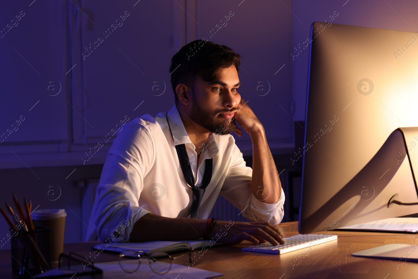 Photo of Tired young man working late in office