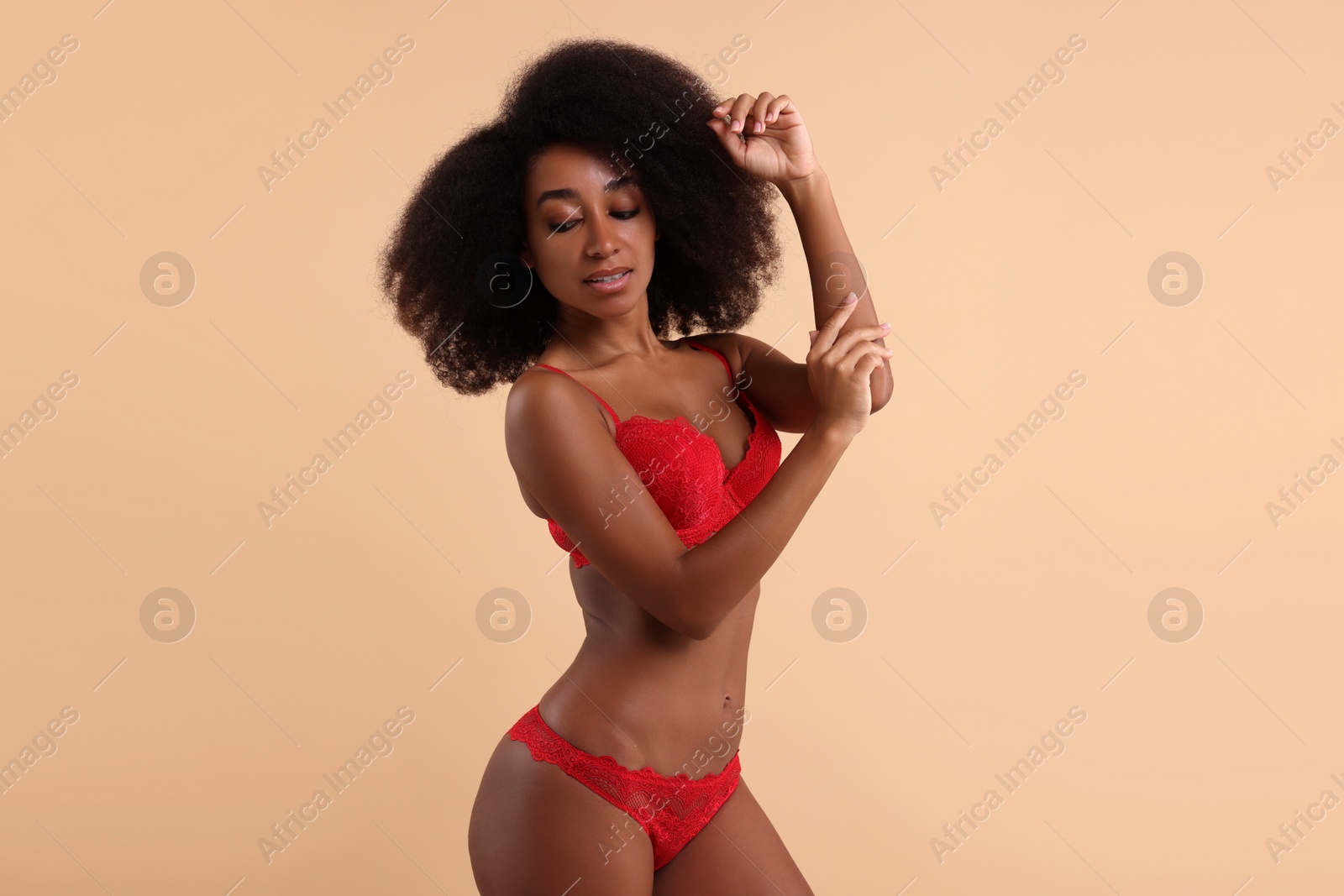 Photo of Beautiful woman in elegant red underwear on beige background