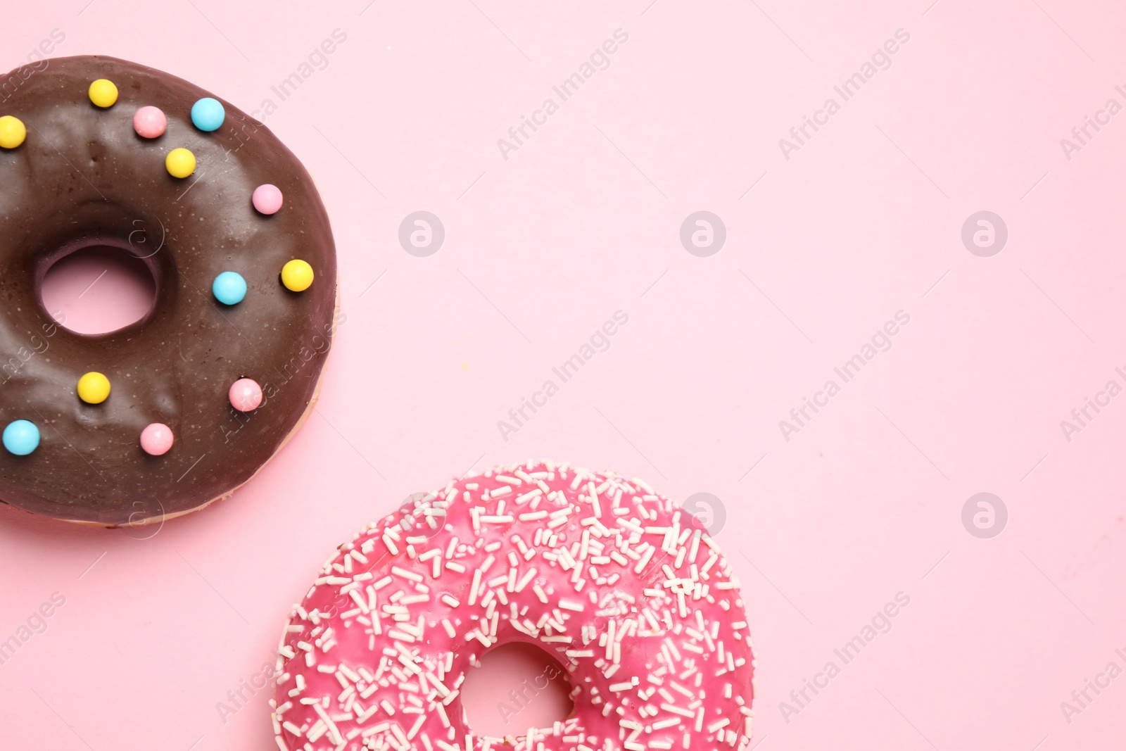 Photo of Delicious glazed donuts on pink background, flat lay. Space for text